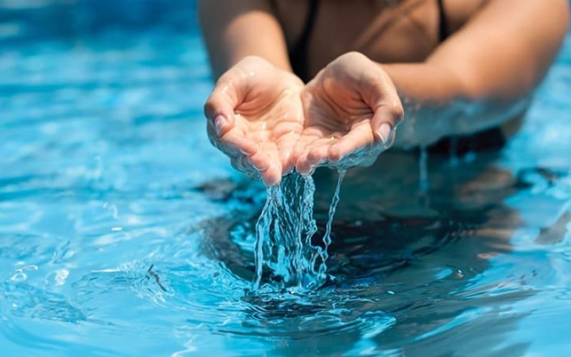 De zwembadbouwers | handen met helder water in zwembad
